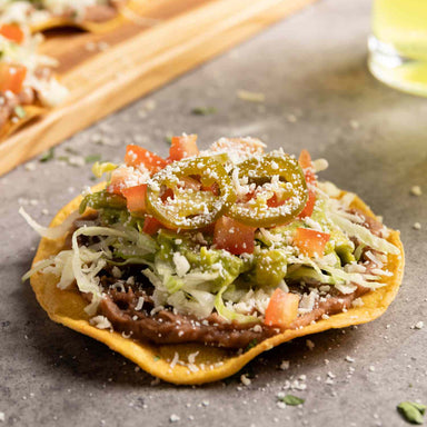 Tortilla chips topped with vegetables on a gray surface